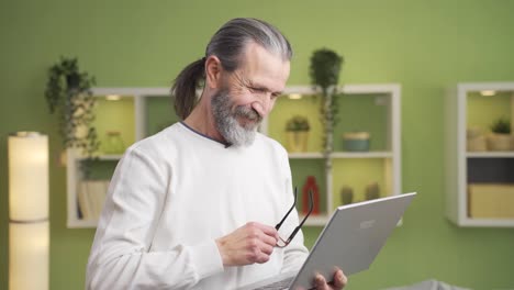 Mature-man-working-at-home-uses-laptop-standing.